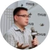 講演中の男性の姿を捉えた写真です。背景には「HUB」の文字が繰り返し表示されており、イベントやセミナーの様子が伺えます。真剣な表情で話す姿から、熱心な講演の雰囲気が伝わってきます。
